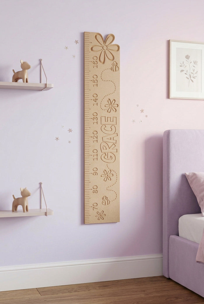 A wooden height chart with floral decorations, intended for measuring a child's height, placed against a plain wall.
